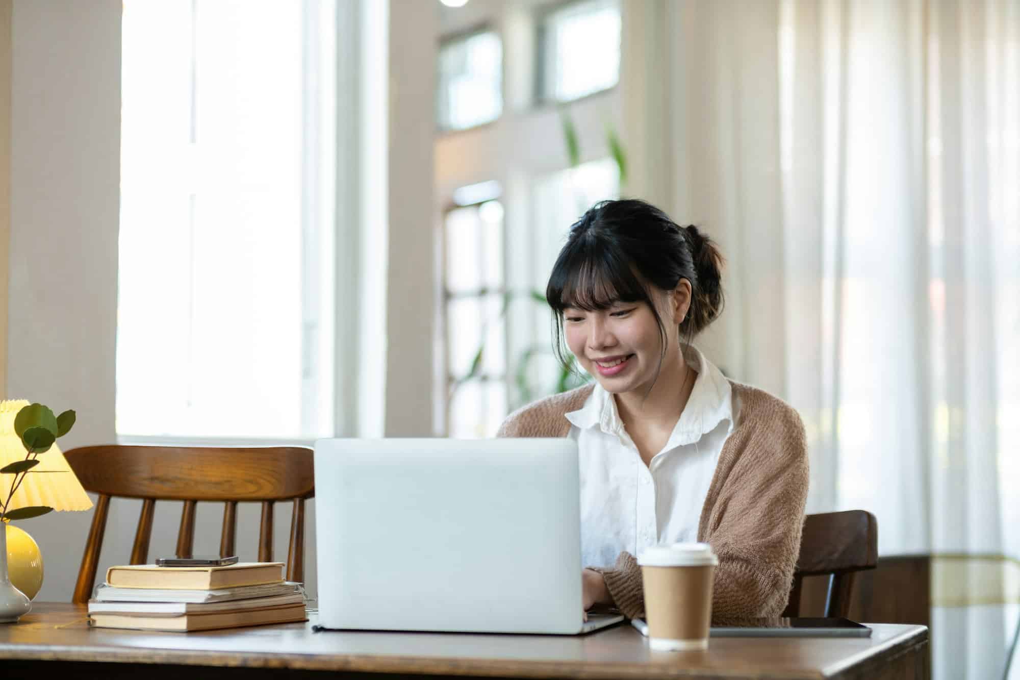 Asian students studying online talking together in an online chat meeting using laptops, studying